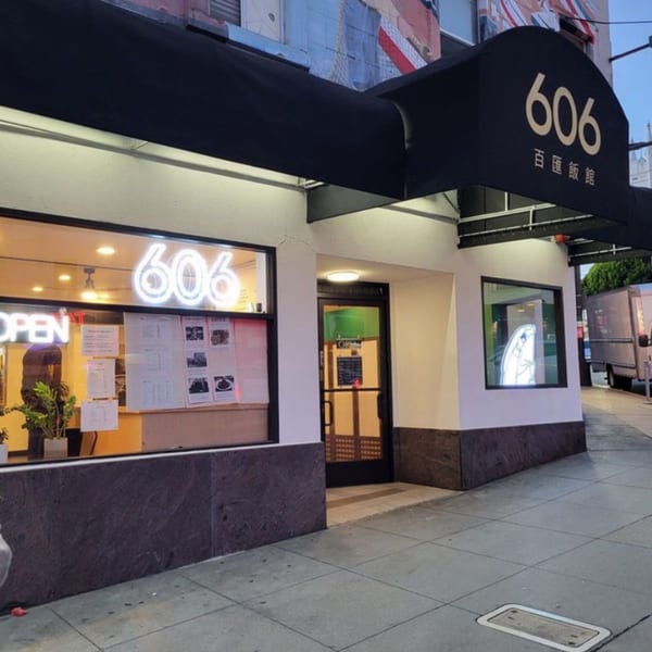 Exterior of 606 Chinese restaurant with a black awning and neon signs in the windows.