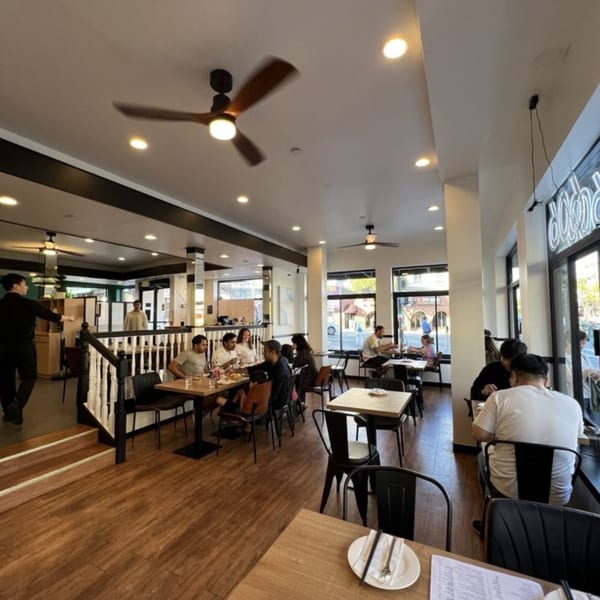The interior of 606, a Chinese restaurant, with patrons seated at tables and a server walking by.